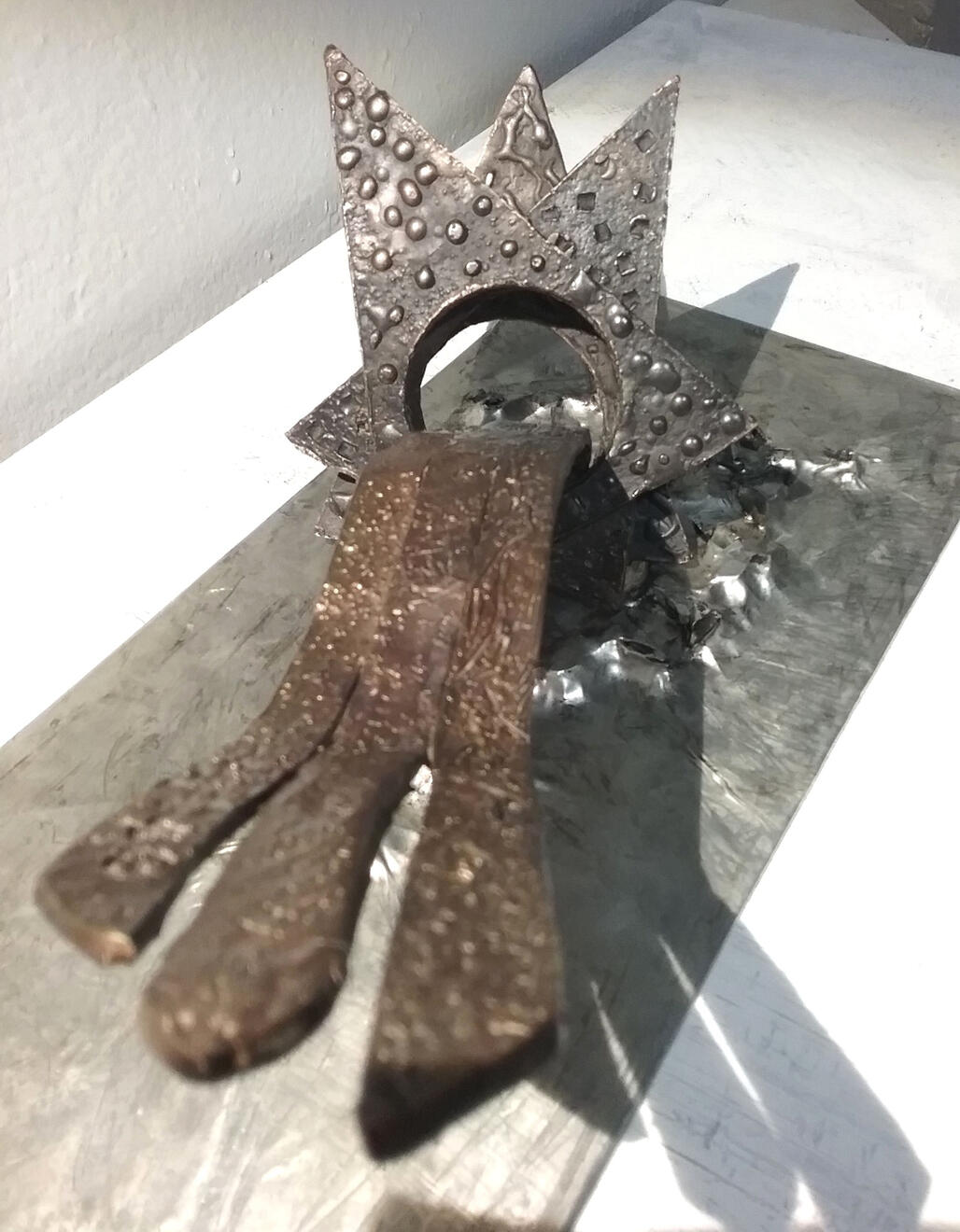 Destellos Escultura destellos, estrella abatida en bronce de frente